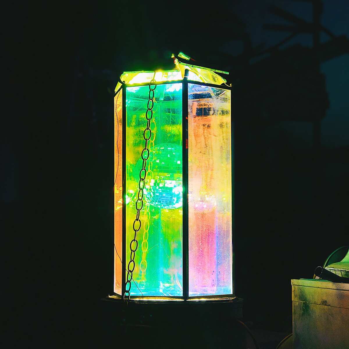 Tabletop lantern prototype — iridescent dichroic panels glowing green and pink
