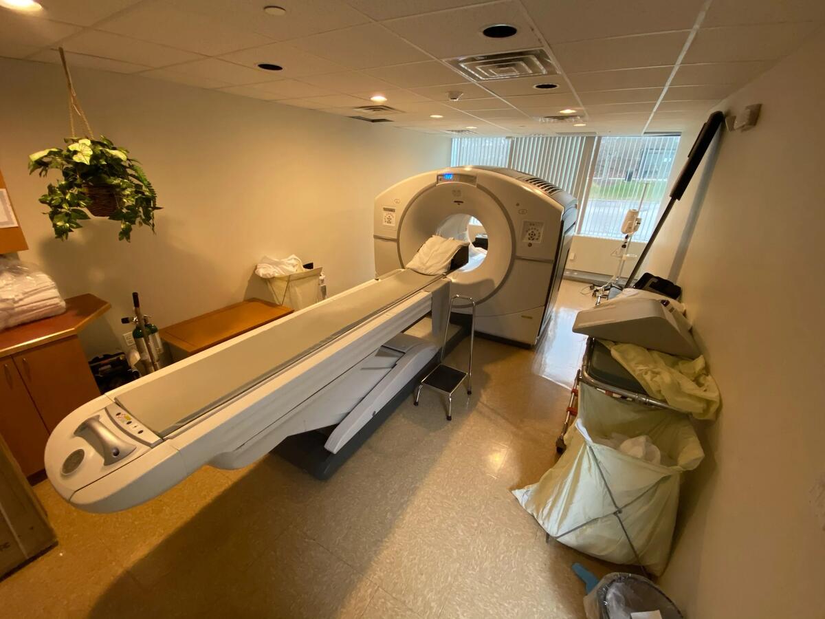 PET/CT scanner room before renovation — dated fluorescent lighting, cluttered