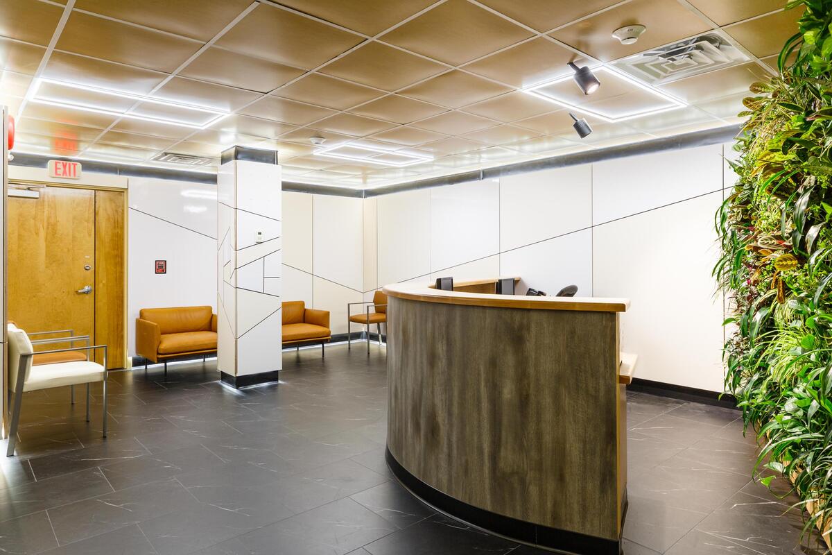 Reception — curved wood desk, living green wall, orange seating